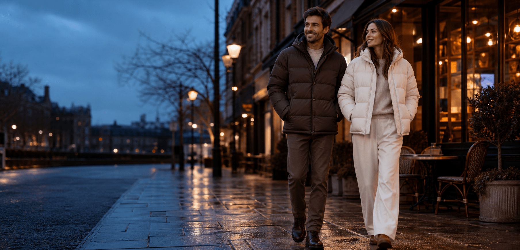 Two people wearing warm down jackets on a softly lit winter city street